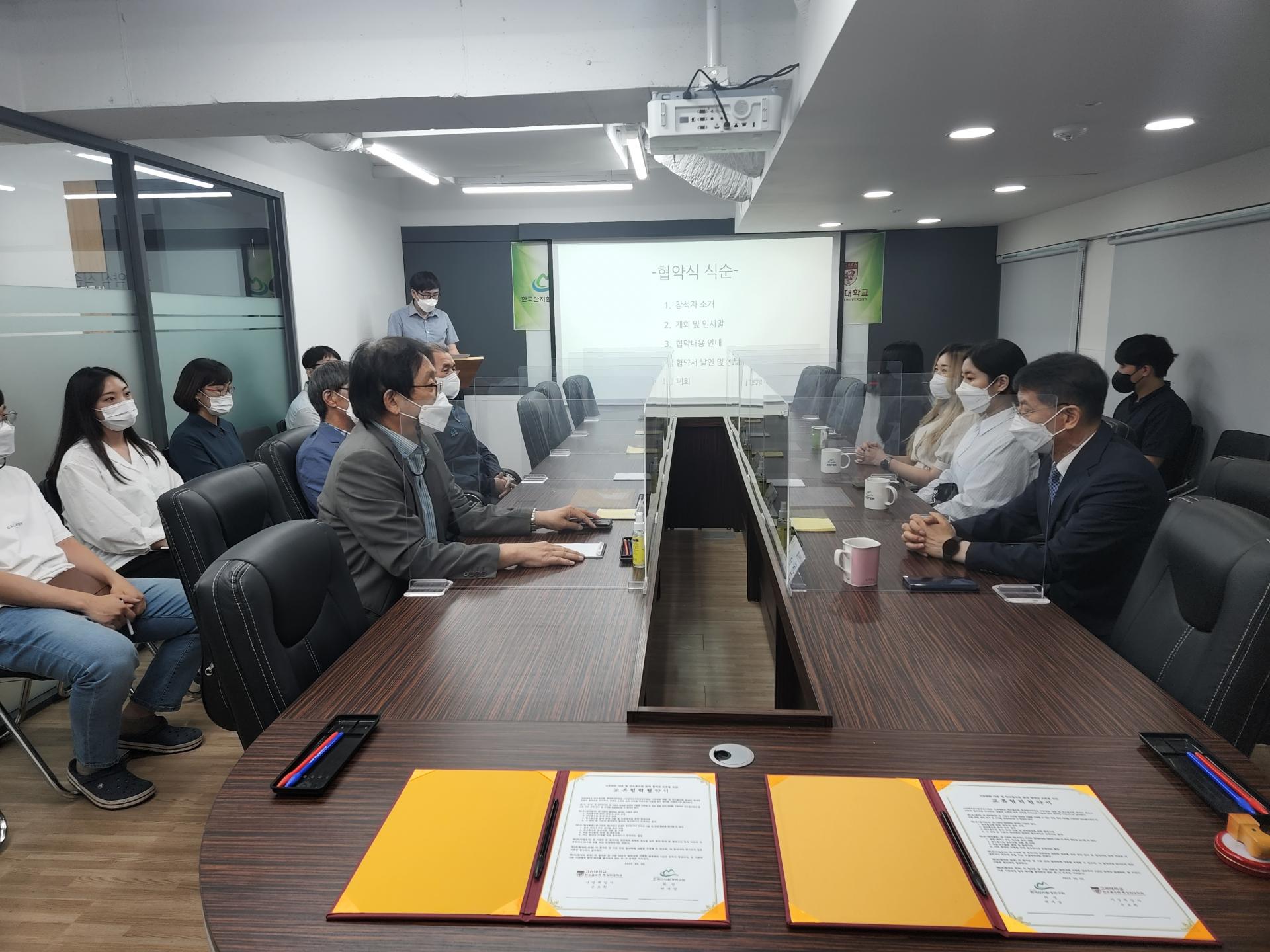 고려대학교 업무협약식: 협약서가 놓인 테이블을 사이에 두고 양측 관계자들이 마주 앉은 모습