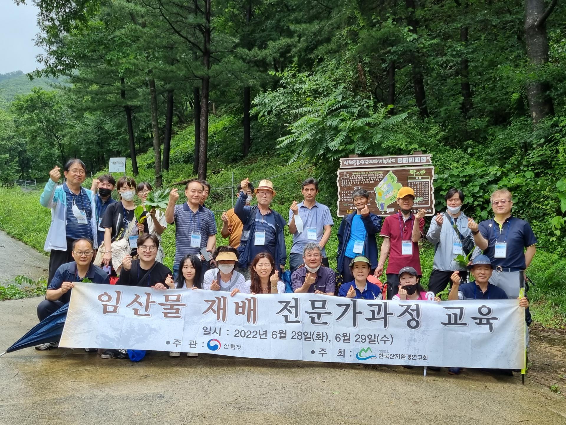 숲길에서 현수막을 들고 단체로 기념하는 수강생들