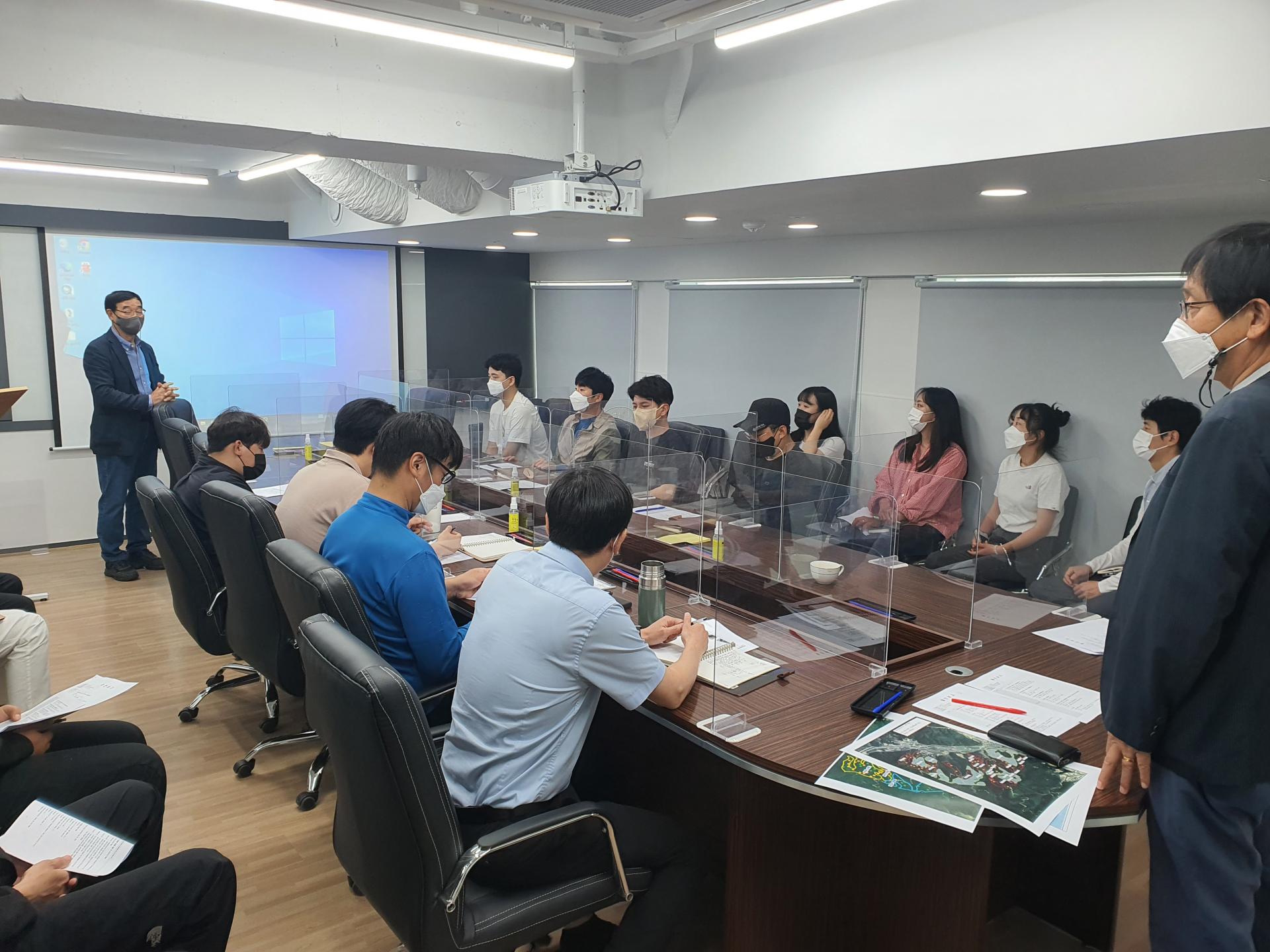 전문가 초빙교육: 직원들이 회의 테이블에 둘러앉아 강의를 듣는 모습