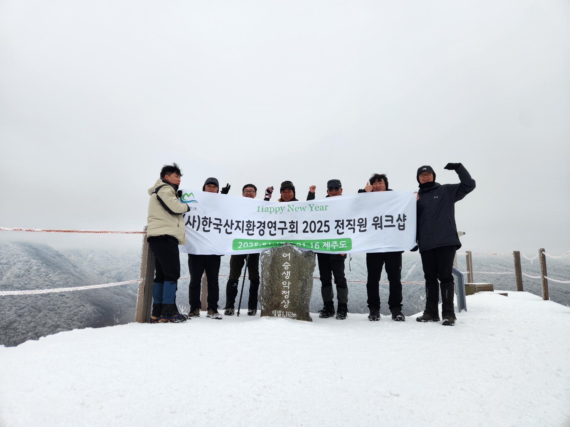 눈 덮인 오름 정상에서 현수막을 들고 기념하는 직원들