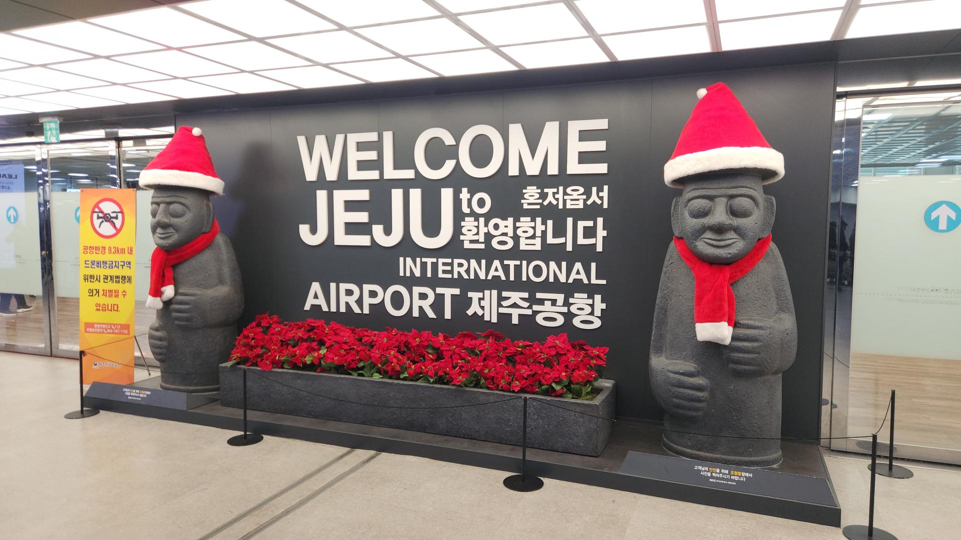 2025 전직원 워크샵 제주 도착: 크리스마스 모자를 쓴 돌하르방 조형물이 있는 제주국제공항 환영 공간